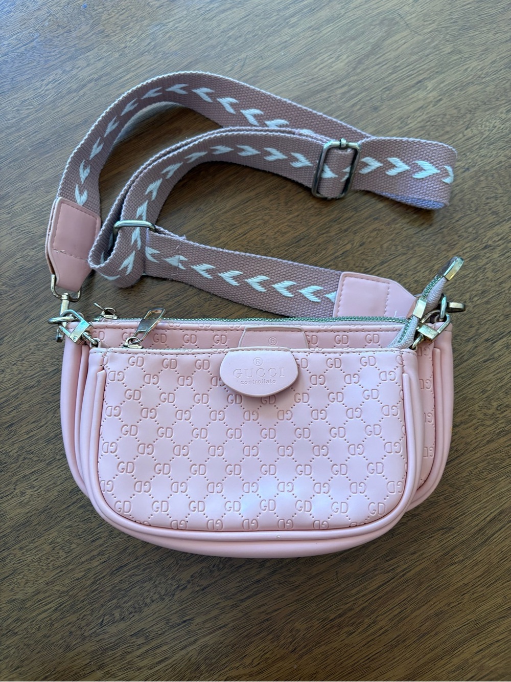 This pink crossbody bag features a distinctive "GD" monogram pattern
